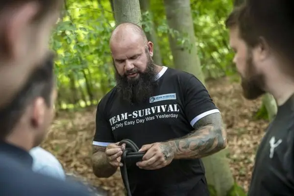 Ein Mann demonstriert Knotentechniken mit einem Seil in einem Wald