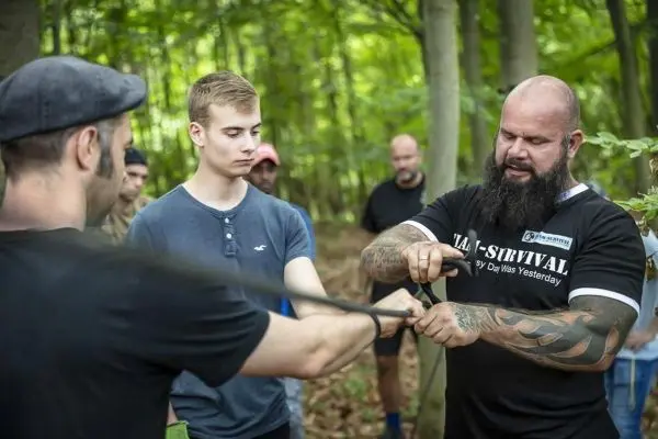 Ein Mann demonstriert Knotentechniken mit einem Seil in einem Wald