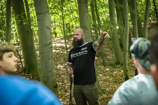 Ein Mann erklärt eine Technik im Wald und zeigt mit der Hand auf einen Punkt