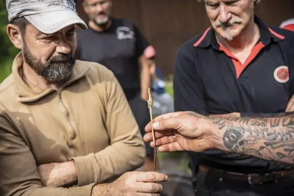 Ein Mann hält einen kleinen, gebogenen Metallgegenstand, während ein anderer ihn betrachtet