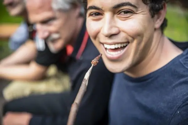 Ein Mann hält einen Stock mit einer angespitzten Spitze und lächelt