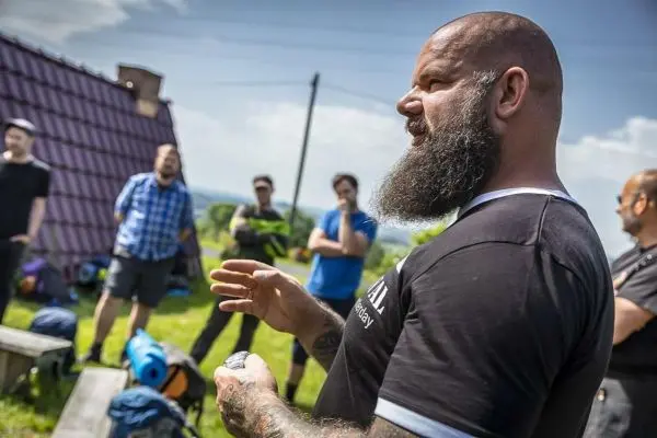 Ein Mann mit Bart erklärt eine Technik, während Teilnehmer mit Rucksäcken zuhören