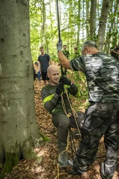 Ein Mann nutzt eine Seilbrücke, während ein anderer ihn sichert