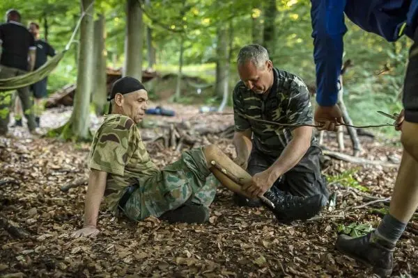 Ein Mann sitzt auf dem Boden und erhält eine medizinische Behandlung am Bein
