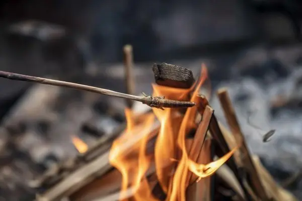 Ein Stock hält ein Stück Zunder über dem offenen Feuer