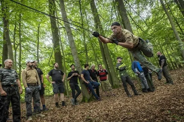 Ein Teilnehmer schwingt an einem Seil durch den Wald, während andere zuschauen
