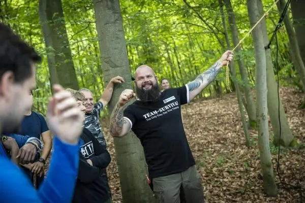 Ein Trainer demonstriert eine Seiltechnik zwischen Bäumen im Wald