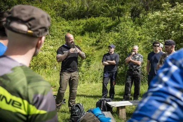 Ein Trainer erklärt Techniken im Freien vor einer Gruppe von Teilnehmern