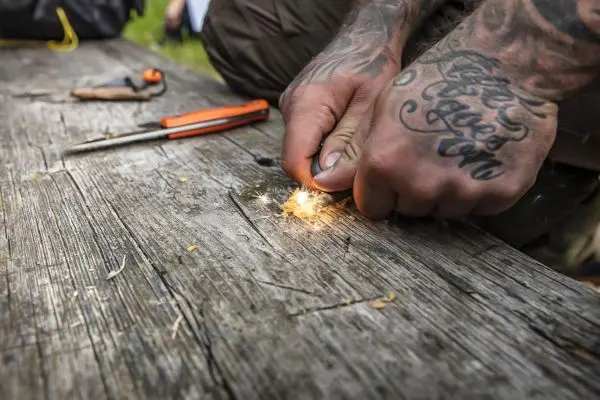 Feuerstahl erzeugt Funken auf einem Holzbrett