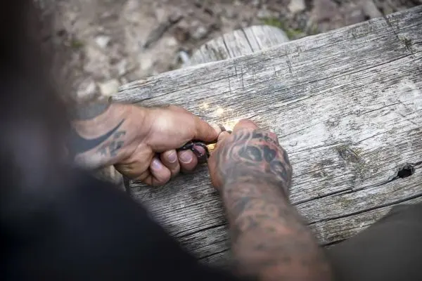 Feuerstahl erzeugt Funken auf einem Holzstück