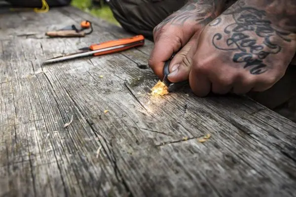 Feuerstahl erzeugt Funken auf Zunder auf einer Holzoberfläche