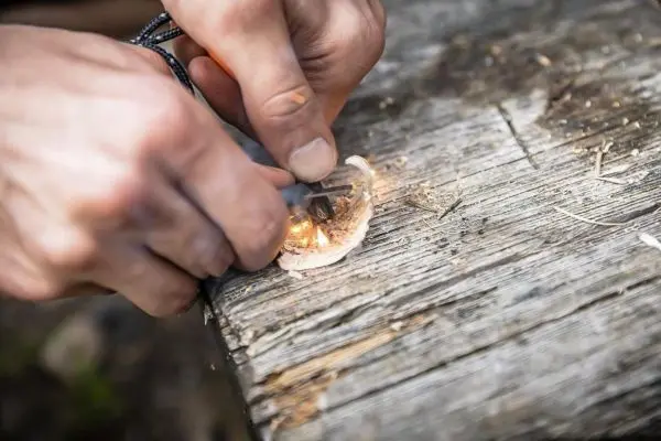 Feuerstahl erzeugt Funken auf Zunder auf einer Holzoberfläche