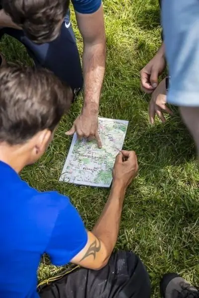 Finger zeigt auf eine Karte, während mehrere Personen um sie herum stehen