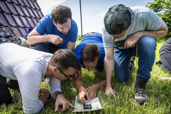 Fünf Personen betrachten gemeinsam eine Karte auf dem Gras