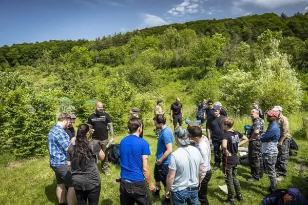 Gruppe diskutiert im Freien, umgeben von Bäumen und Grünflächen