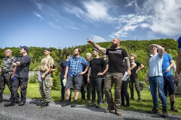 Gruppe von Personen beobachtet eine Demonstration im Freien, einige halten Unterlagen in der Hand