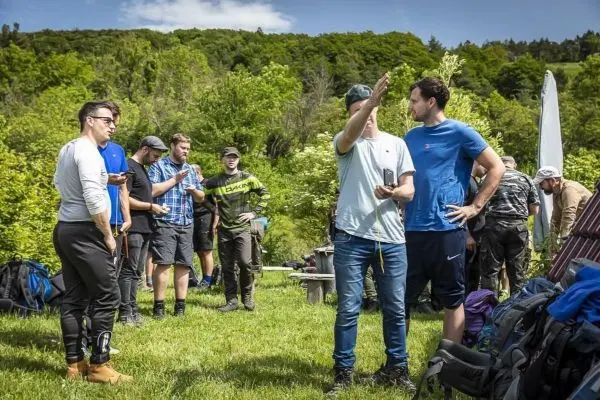 Gruppe von Personen diskutiert im Freien, Rucksäcke liegen auf dem Boden