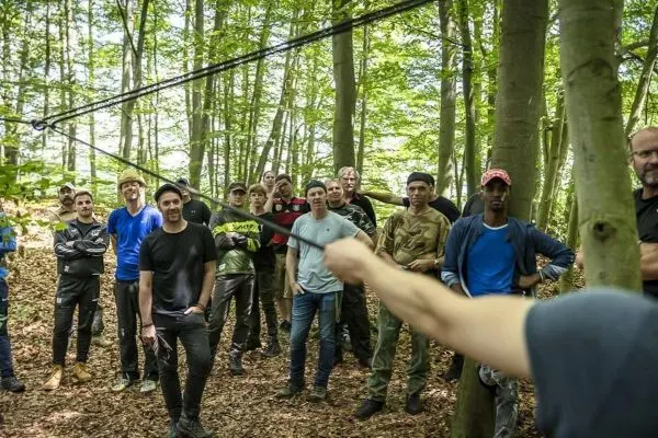 Gruppe von Personen hört einem Trainer im Wald zu