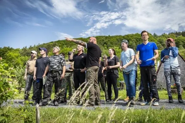 Gruppe von Personen steht auf einem Weg und beobachtet eine Demonstration im Freien