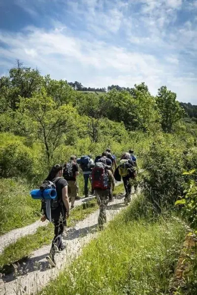 Gruppe von Wanderern mit Rucksäcken auf einem schmalen Weg durch die Natur