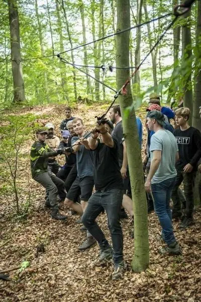 Gruppe zieht an einem Seil zwischen Bäumen beim Überlebenstraining