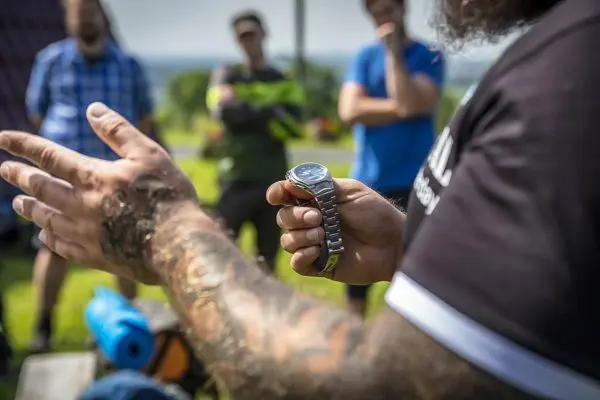 Hand zeigt auf Armbanduhr während einer Präsentation im Freien