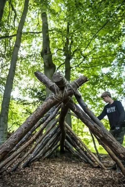 Holzkonstruktion aus Ästen bildet eine Tarp-Notunterkunft im Wald