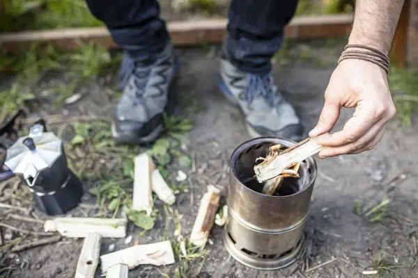 Holzstück wird in einen Hobo-Kocher eingelegt, um ein Feuer zu entfachen
