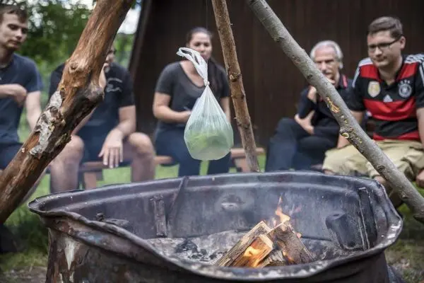 Kessel mit Wasser hängt über dem Feuer in improvisierter Aufhängung