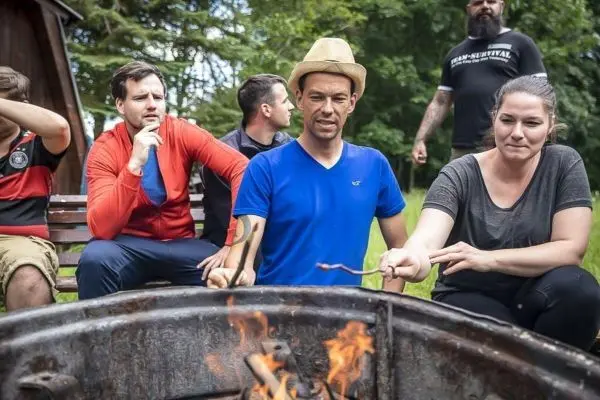 Männer und Frauen sitzen um ein Feuer und halten Stöcke über die Flammen