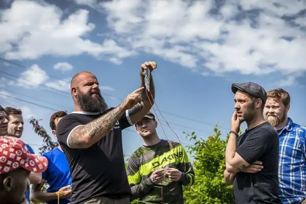 Mann demonstriert eine Technik mit einem Gerät und Schnüren vor einer Gruppe