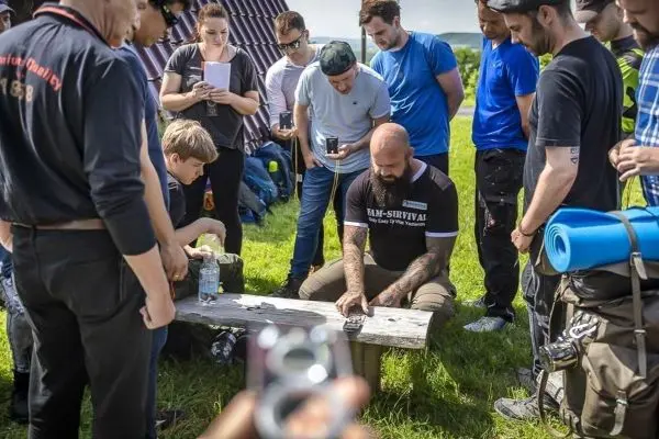 Mann demonstriert Techniken auf einem Tisch, umgeben von interessierten Zuschauern