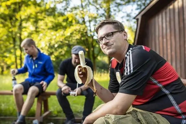 Mann hält eine Banane in der Hand, während er auf einer Bank sitzt