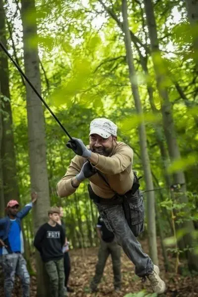 Mann nutzt Seil für eine Seilbrücke zwischen Bäumen im Wald