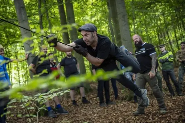 Mann nutzt Seil für eine selbstgebaute Seilbrücke im Wald