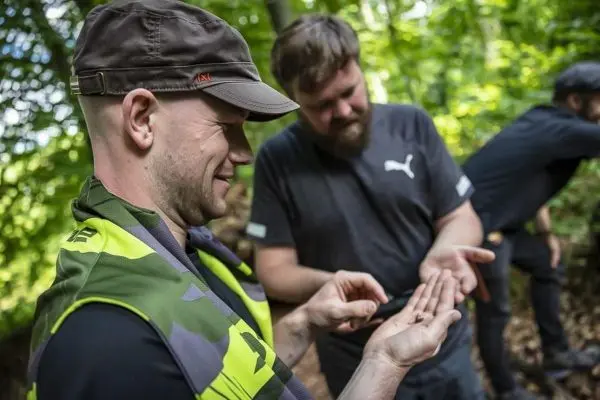 Mann untersucht kleine Objekte in der Hand, während ein anderer zuschaut