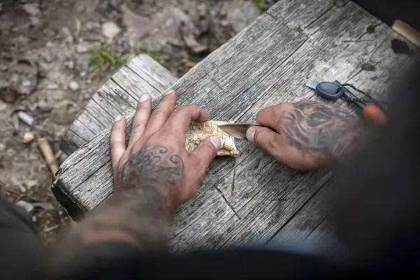 Messer schneidet Holzstück auf einer Holzoberfläche