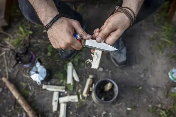 Messer schneidet Holzstück für Zunder in der Natur
