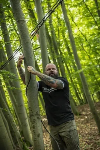 Person befestigt ein Seil an einem Baumstamm im Wald