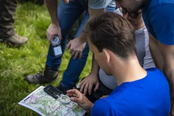 Person betrachtet Karte und Kompass in Gruppe