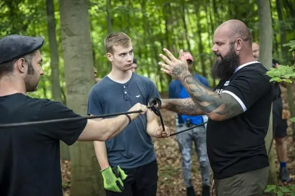 Person erklärt eine Technik mit einem Seil im Wald