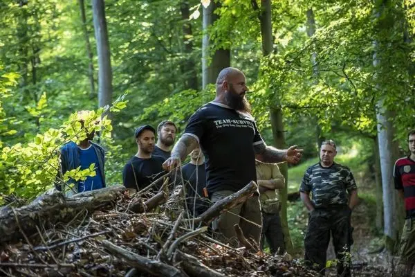 Person erklärt eine Technik vor einer Gruppe im Wald