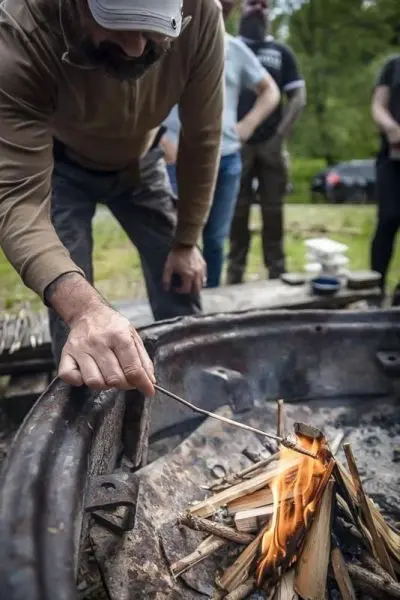 Person fügt Holzscheite in ein Feuer