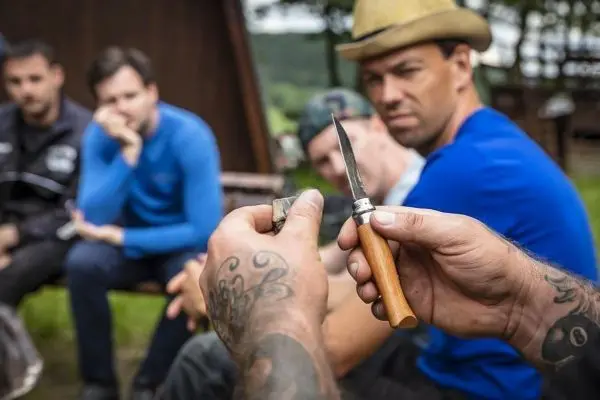 Person hält ein Messer und zeigt es einer Gruppe