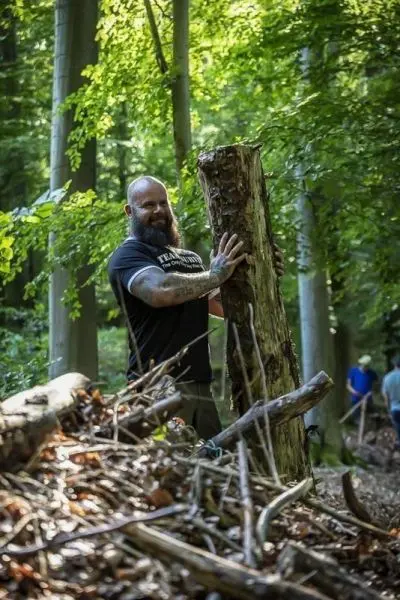 Person hebt einen Baumstamm im Wald an