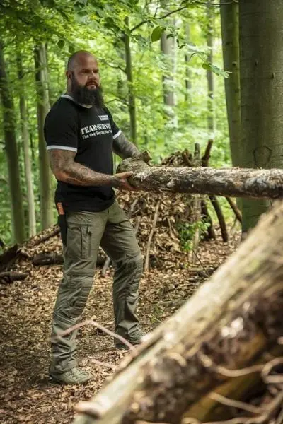 Person hebt einen Baumstamm im Wald an