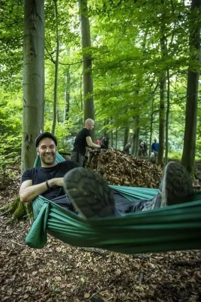 Person liegt entspannt in einer Hängematte im Wald
