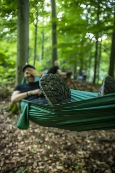 Person liegt entspannt in einer Hängematte im Wald