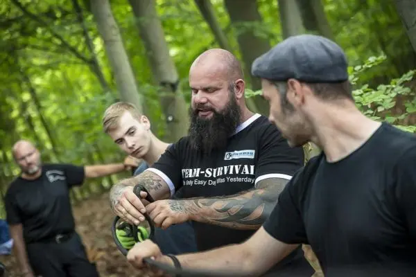 Person zeigt anderen Personen eine Technik im Wald