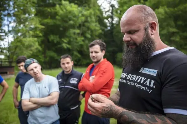Person zeigt etwas in der Hand, Gruppe schaut aufmerksam zu beim Survival Training